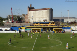 Blick aufs Spielfeld und Hafengelände beim Spiel Dock Sud gegen Colegiales im Estadio de los Inmigrantes, April 2022